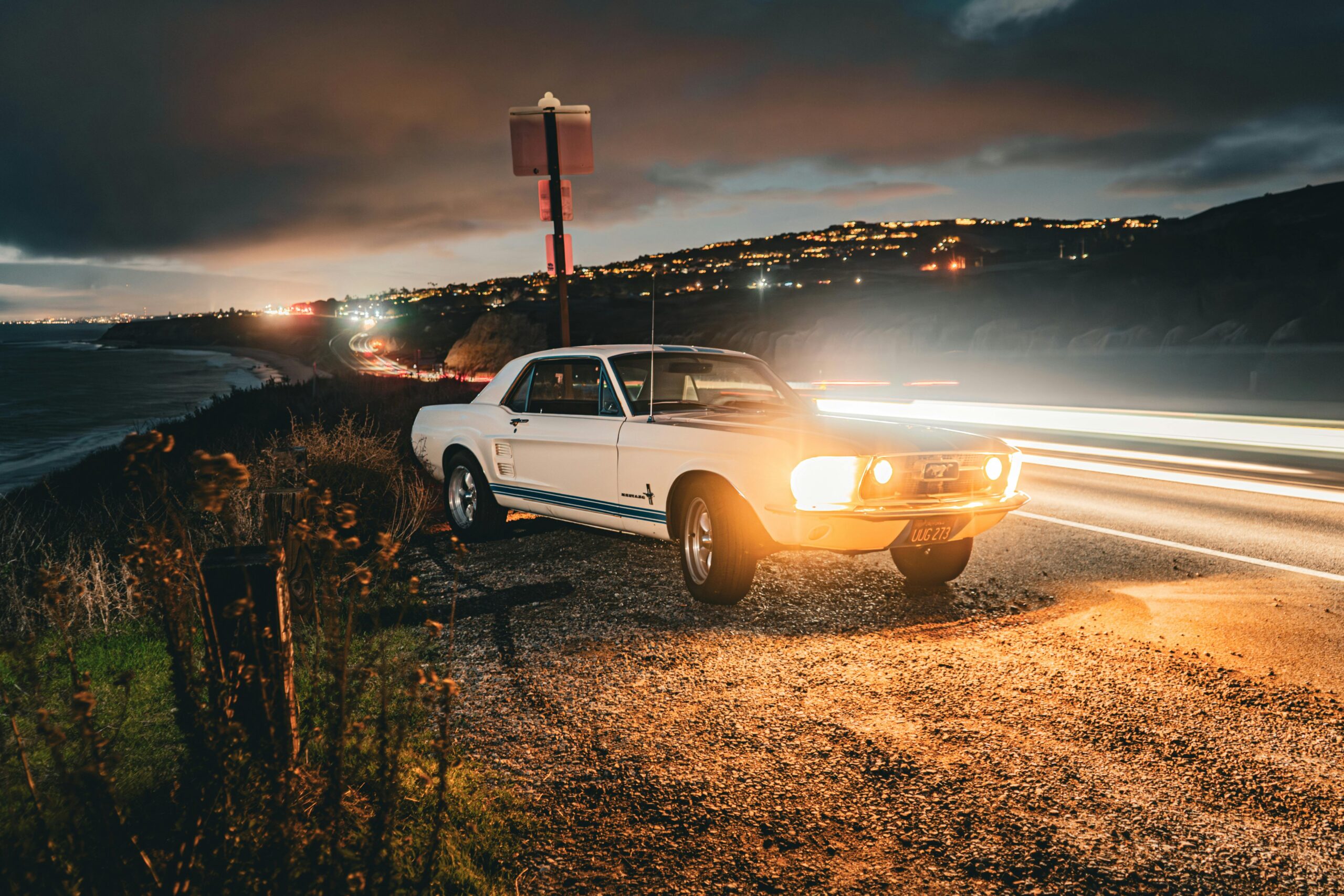 Classic Mustang illuminated by coastal road lights at night in Newport Beach, CA.